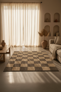 A rectangular area rug with a beige and brown checkerboard pattern is displayed in a modern, sunlit living room with a sofa, coffee table, and sheer curtains.