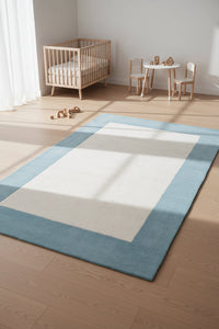 A rectangular area rug with a light blue border and a large off-white central panel, shown flat against a white background.