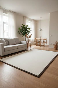 An off-white rectangular rug with a dark brown border, filling the entire frame.