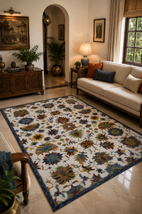 A large rectangular area rug with an intricate floral and botanical pattern in blue, mustard yellow, brown, and cream, styled in a warm, modern living room next to a beige sofa